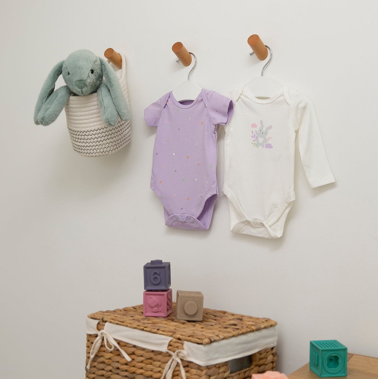 wei Baby Bodys mit Herzchen- und Häschen-Print in einem liebevoll eingerichteten Kinderzimmer.