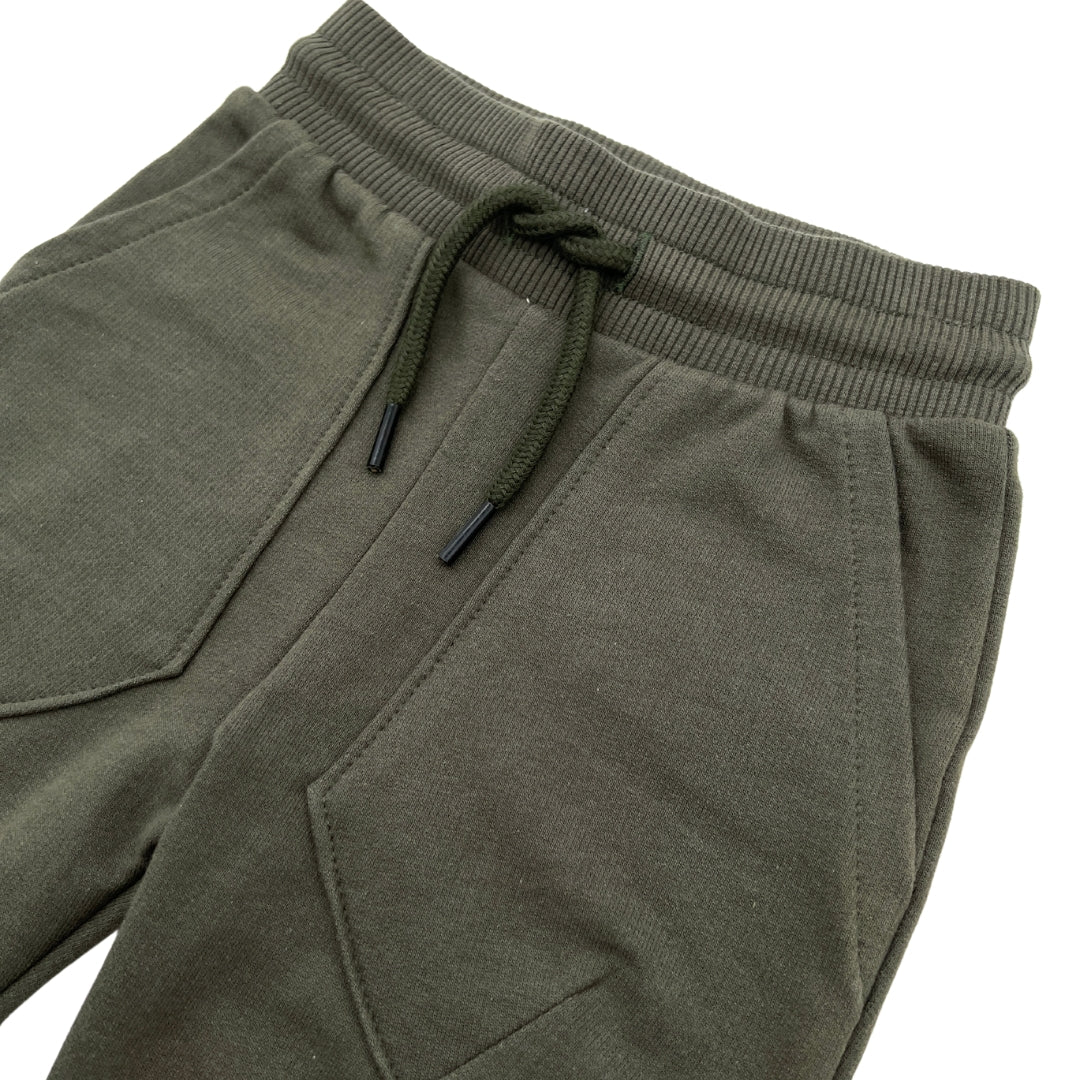 Nahaufnahme der dunkelgrünen Abenteuerer Jogginghose für Jungs mit praktischen Taschen