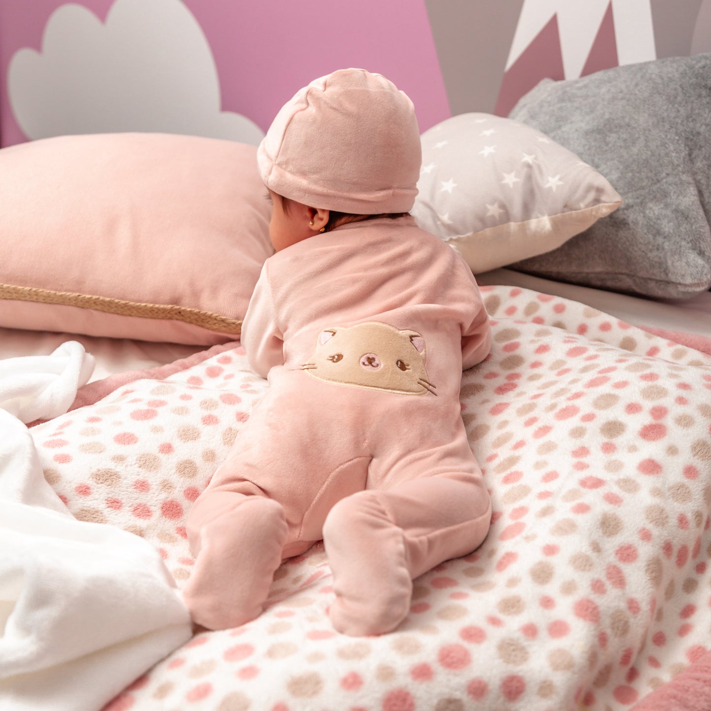 Baby-Mädchen trägt das rosa Baby Set mit Zip-up Strampler, Body mit Katzen-Motiv, Mütze und Socken – Rückansicht.