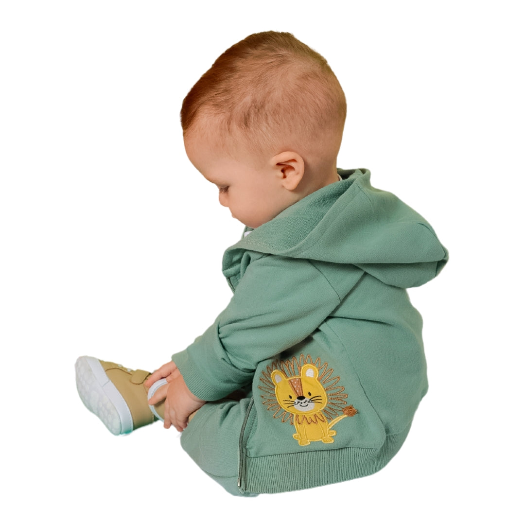 Baby von der Seite mit grünem Hoodie, der Löwen-Stickerei zeigt