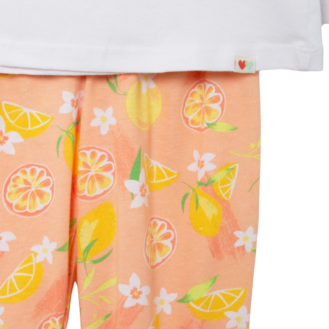 Nahaufnahme des lebhaften Musters aus Zitronen, Orangen und Blumen auf der orangefarbenen Hose