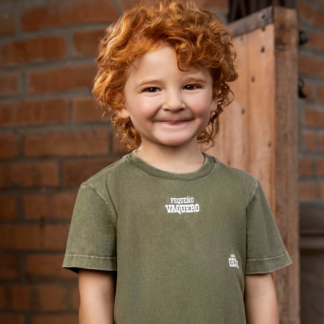 Glückliches Kind trägt kurzärmliges T-Shirt in trendigem Militärgrün, lächelnd und voller Freude.