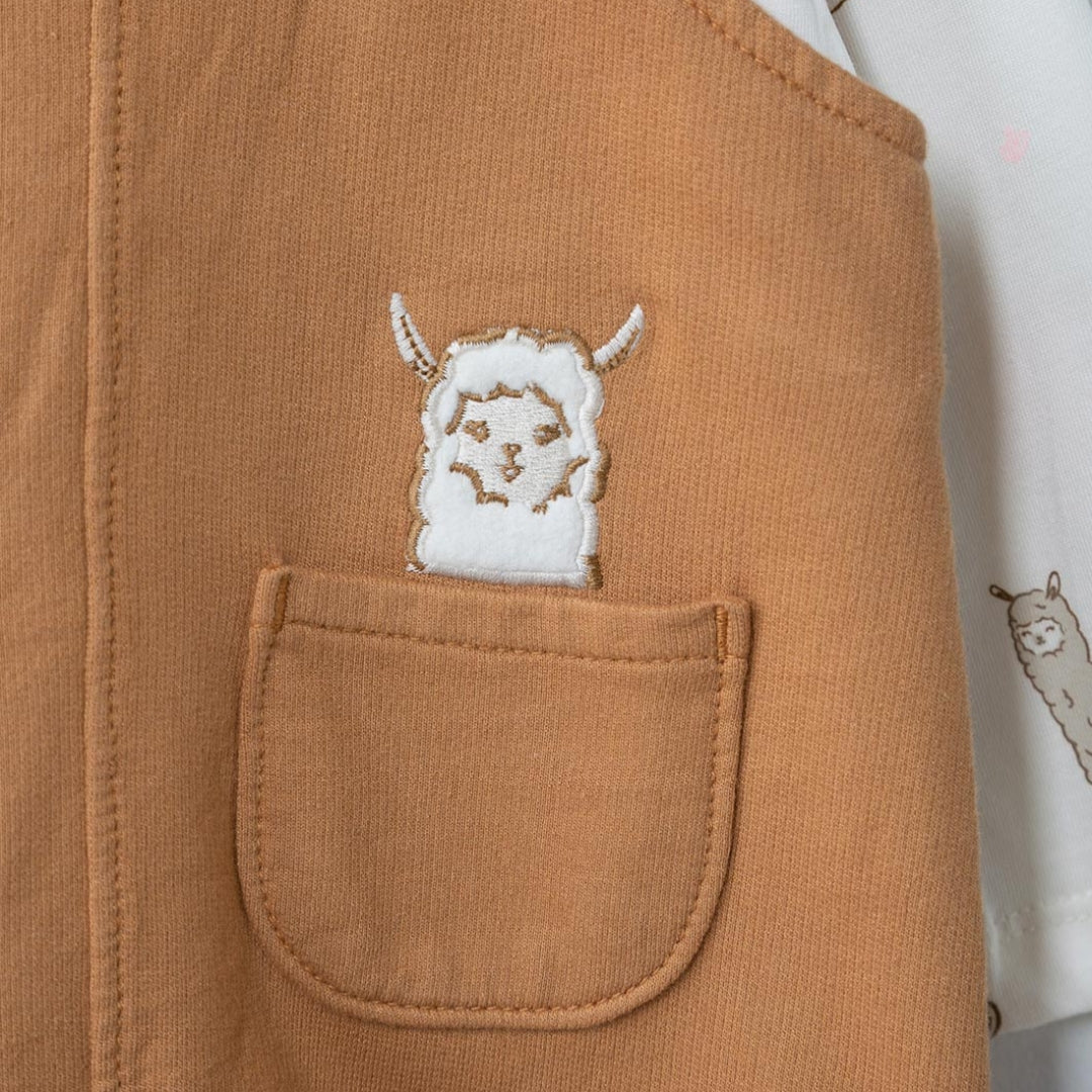 Nahaufnahme der bestickten Llama-Tasche auf dem braunen Latzkleid