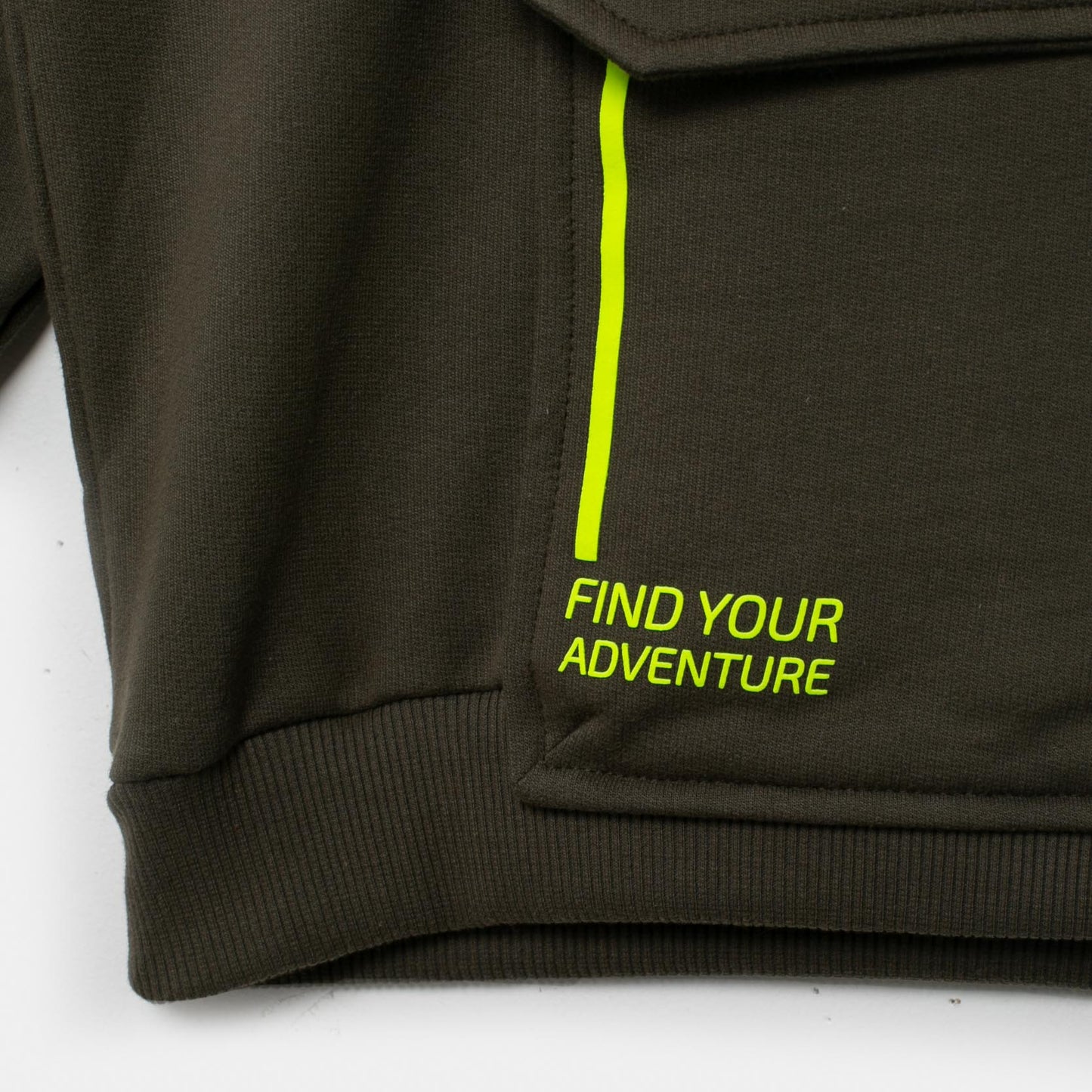 Nahaufnahme des neonfarbenen Details des Abenteuer Hoodies, das den Reißverschluss und den Schriftzug "FIND YOUR ADVENTURE" zeigt.
