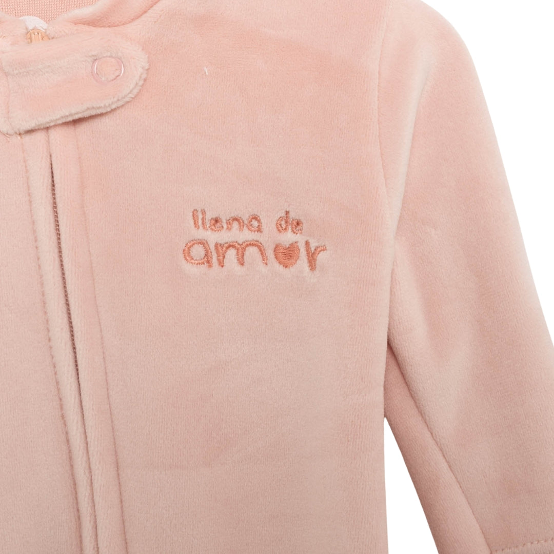 Nahaufnahme des Zip-up Stramplers in Rosa mit samtiger Oberfläche und „Un nuevo día“-Stickerei.