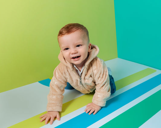Baby krabbelt fröhlich in weicher Babyver Plüschjacke – bequeme Kleidung für kleine Entdecker