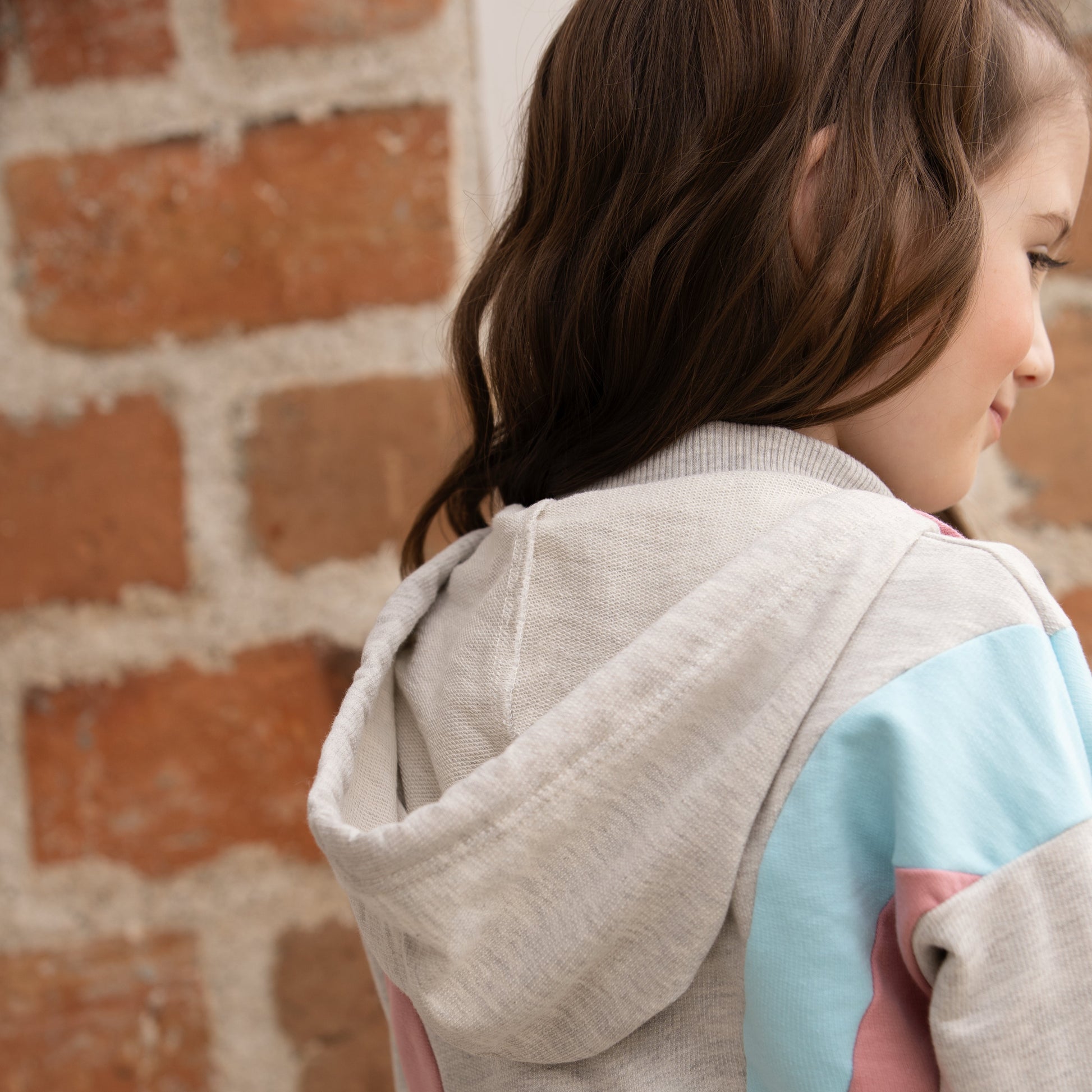 Mädchen trägt den Pastelltraum Hoodie in Grau, zeigt das Design von hinten.