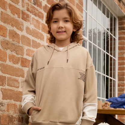 Fröhlicher Junge trägt den Elfenbein Hoodie, der mit elfenbeinfarbenen Einsätzen und versteckten Taschen begeistert.